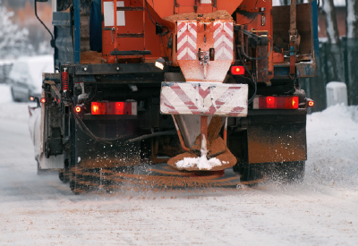 Snow plow spreader applying deicer to an icy roadway